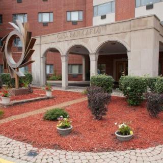 A building entrance with decorative landscaping and a modern sculpture.