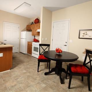 A cozy kitchen and dining area featuring a small round table with two chairs, an oven, and a refrigerator.