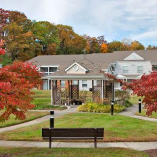 A scenic park setting with a bench and vibrant autumn foliage in front of a building.