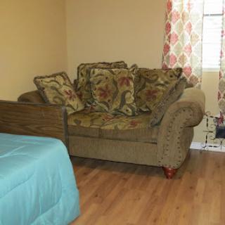 A cozy living space featuring a decorative couch with pillows and a window adorned with colorful curtains.
