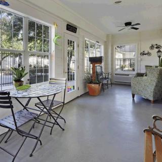 A bright sunroom with large windows, comfortable seating, and indoor plants.