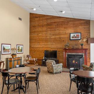 A cozy living room with wood paneling, featuring a fireplace, television, and comfortable seating.