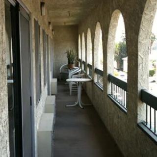 A long balcony corridor with arched openings and minimal furniture.