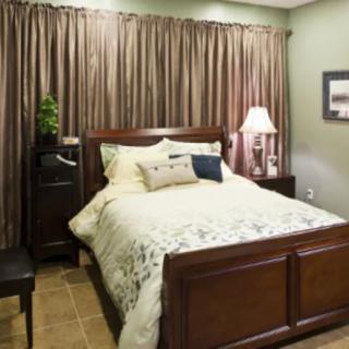 A cozy bedroom with a neatly made bed, wooden furniture, and soft lighting.