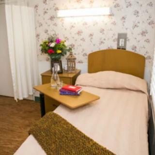 A cozy hospital room with a single bed, adorned with flowers and a blanket.