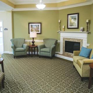 Cozy living room with armchairs and a sofa around a fireplace.