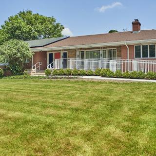 A suburban brick house with a well-maintained lawn and landscaping.