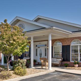 A suburban house with a porch and columns under a clear blue sky.