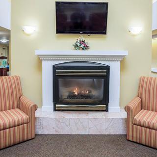 A cozy living room setup with a fireplace, two striped chairs, and a television mounted above.