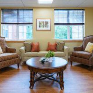 A cozy living room with two armchairs, a sofa, and a wooden coffee table in front of large windows.