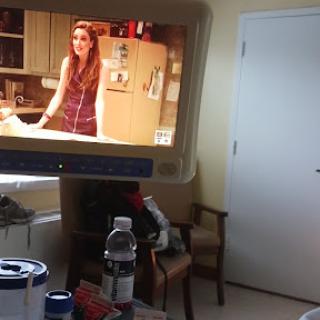 A living room scene featuring a TV displaying a woman in a kitchen setting.