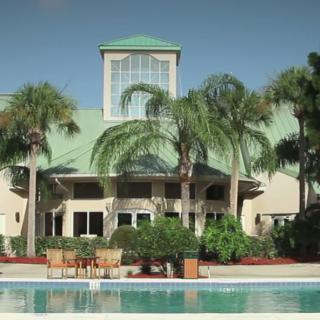 A tropical resort building surrounded by palm trees, overlooking a pool.