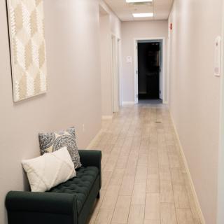 A modern hallway featuring a small sofa with pillows and artwork on the wall.