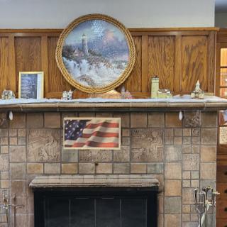 A cozy home interior featuring a rustic fireplace adorned with an American flag and decorative items.
