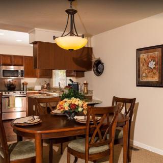 Cozy dining area connected to a modern kitchen with wooden furniture and warm lighting.