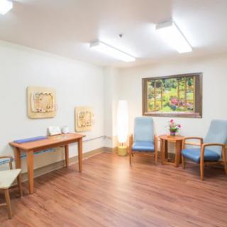 A cozy waiting room with chairs, a table, and artwork on the walls.