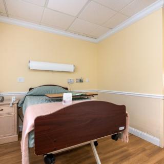 A clean and well-organized hospital room featuring a single bed.