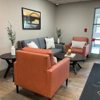 A cozy waiting area featuring modern furniture, with an inviting atmosphere created by the use of soft colors and decorative plants.