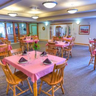 A cozy dining room with pink tablecloths and wooden furniture, set up for a meal.