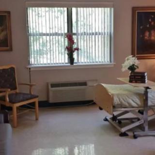 A clean and well-lit hospital room with a bed, chair, and decorative elements.