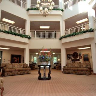 A spacious lobby with elegant decor, featuring a central chandelier and comfortable sitting areas.