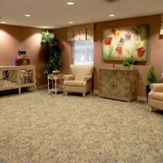 A cozy lobby area with armchairs, decorative plants, and artwork on the walls.