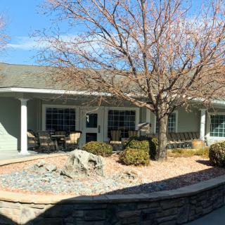 A sunny view of a building with a landscaped patio and trees.
