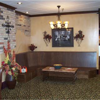A cozy restaurant lobby featuring wooden furniture, decorative wall art, and warm lighting.