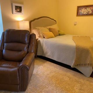 A cozy bedroom with a comfortable bed and a brown leather recliner.