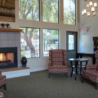 A cozy living room featuring a fireplace, comfortable chairs, and large windows.