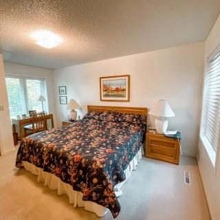 A cozy bedroom with a large bed, nightstands, and lamps, featuring a floral bedspread and a painting above the headboard.