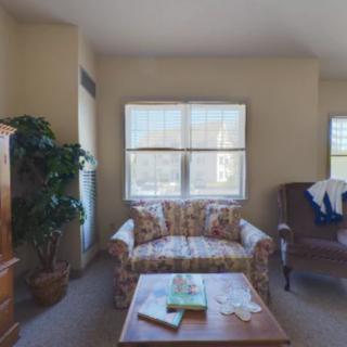A cozy living room with a sofa, armchair, and coffee table in front of a large window.