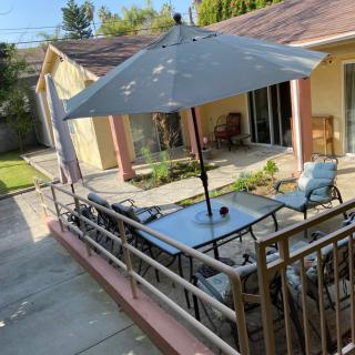 A sunny backyard patio with outdoor seating and an umbrella.