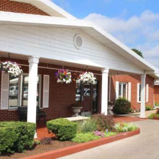 A well-maintained building with a brick exterior featuring an inviting entrance adorned with hanging flowers and columns.
