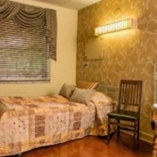 Cozy bedroom with a single bed, decorated with patterned wallpaper and a wooden chair.