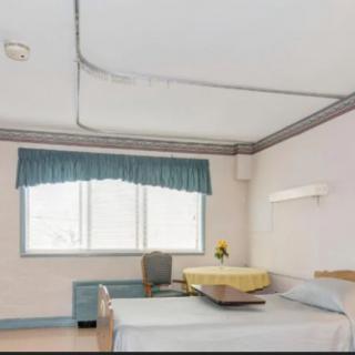 A clean and organized hospital room with a single bed, chair, and window.