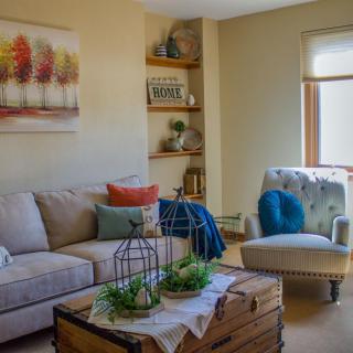A cozy living room with a neutral color palette, featuring a comfortable sofa, armchair, and colorful decor accents.