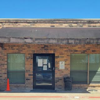 Front view of a brick office building with a dark awning and a single entrance door.