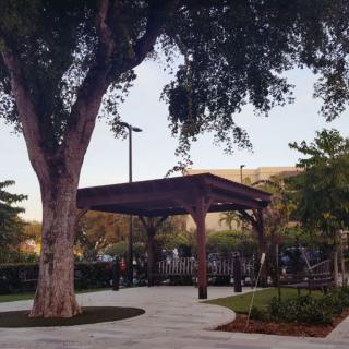 A peaceful park scene with a pavilion, surrounded by trees and a winding pathway.