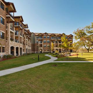 A modern apartment building with a landscaped lawn and pathway under a clear blue sky.