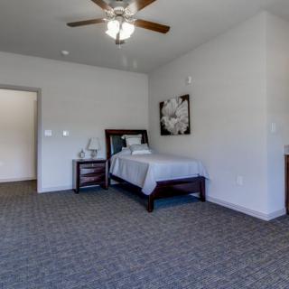 A minimalist bedroom with a single bed, nightstand, and carpeted floor.