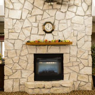 A cozy stone fireplace with a clock and autumn decor on the mantel.