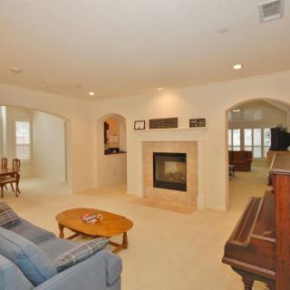A cozy living room with a fireplace, featuring a sofa, coffee table, and piano.