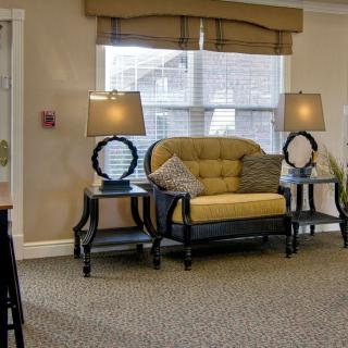 A cozy living room with a yellow sofa, two lamps on side tables, and a large window.