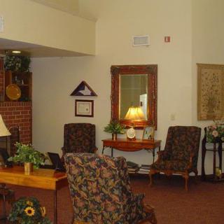 A cozy living room setting with comfortable chairs, a lamp on a side table, and decorative plants.