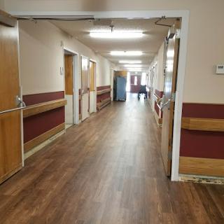 A spacious hospital hallway featuring wooden flooring and well-lit surroundings.