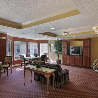 A spacious living room with a television, seating area, and large windows.