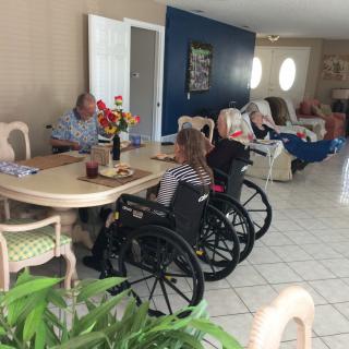 A group of seniors sitting around a dining table in a care home setting.