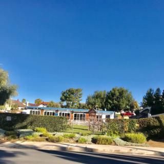 A scenic view of a building surrounded by lush gardens and trees under a clear blue sky.