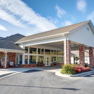 A well-maintained building entrance with brick accents and a covered driveway under a clear sky.